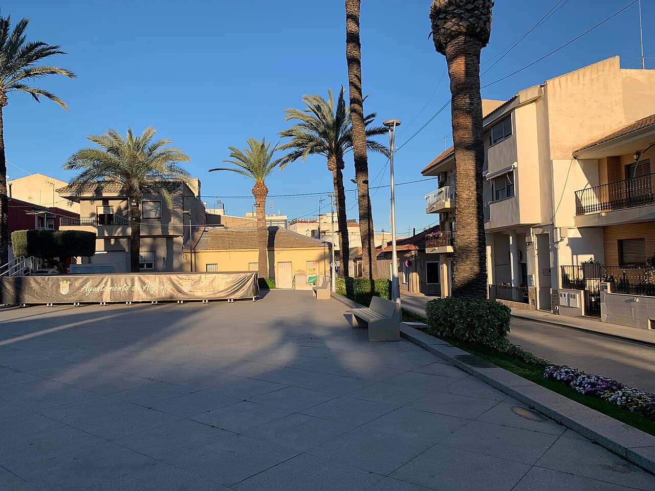 Het dorpsplein van Algorfa met palmen en het bord van het stadhuis